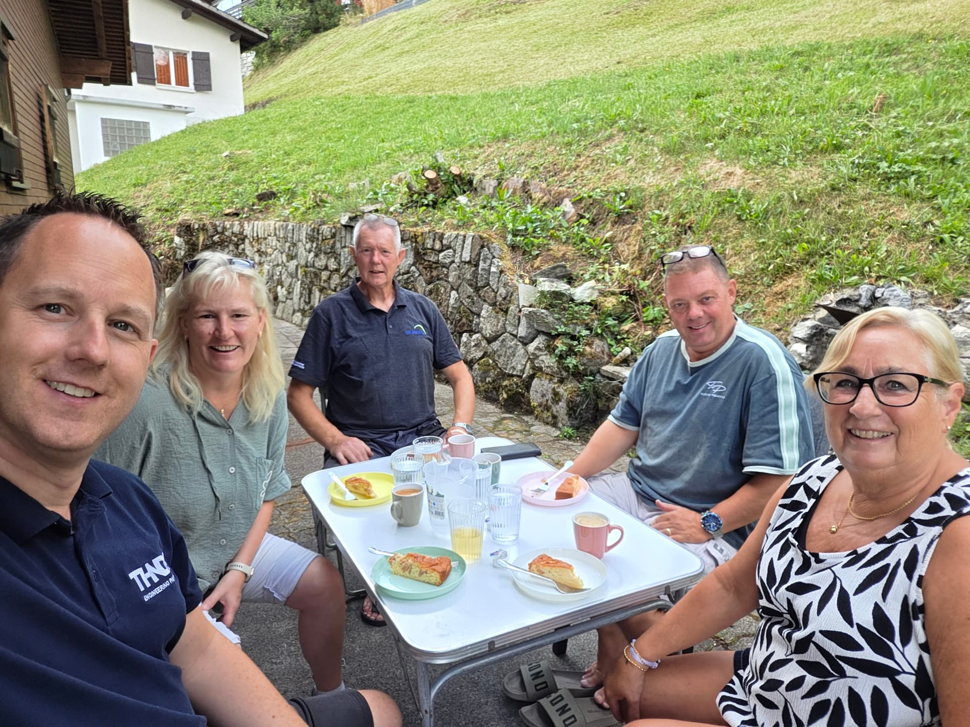 Klussers aan tafel voor het chalet met koffie en taart